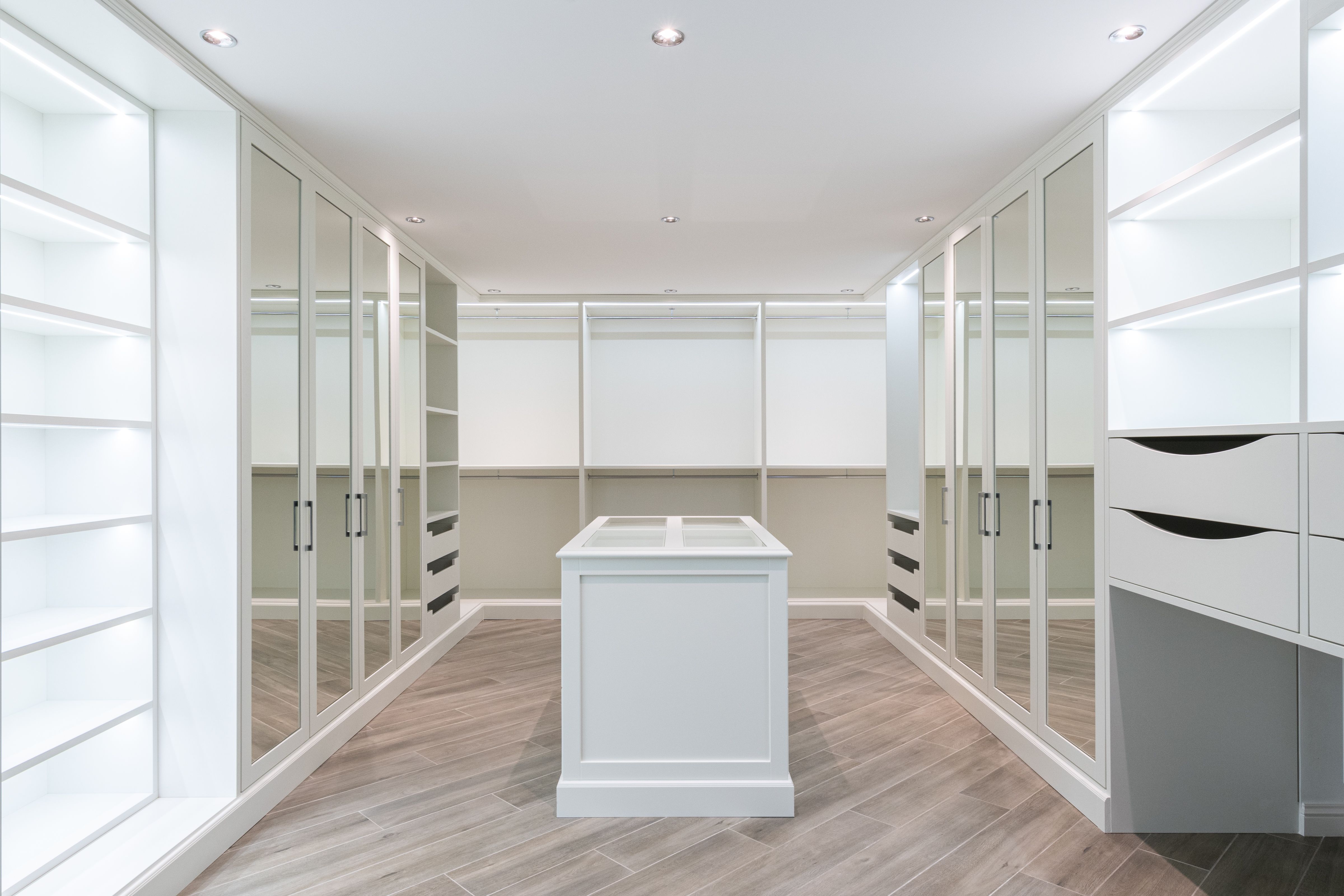 Bright walk-in closet with mirrored doors and a central island